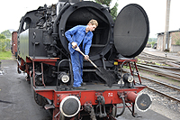 Ein Arbeiter entfernt bei geöffneter Rauchkammer die 'Lösche', also den Ruß, aus einer Dampflok im Betriebswerk HeilbronnHandarbeit: Ein Arbeiter entfernt bei geöffneter Rauchkammer die 